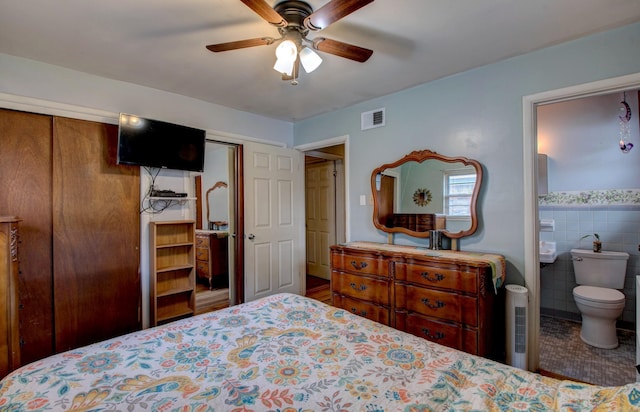 111 Greenland Cv, Little Rock, AR 72204 - tiled bedroom with tile walls, ceiling fan, ensuite bathroom, and wainscoting