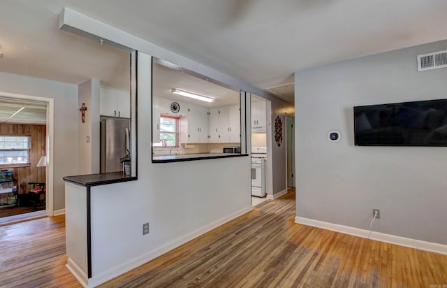 111 Greenland Cv, Little Rock, AR 72204 - kitchen with freestanding refrigerator, white cabinets, wood finished floors, dark countertops, and white gas range oven