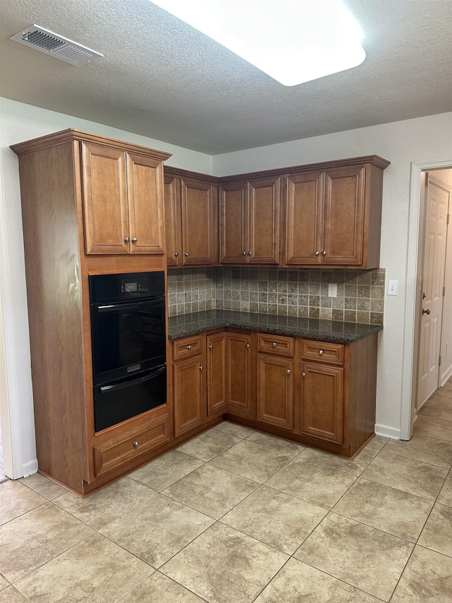 3505 Stockton Dr, Benton, AR 72015 - kitchen featuring oven, a warming drawer, decorative backsplash, brown cabinetry, and dark stone counters