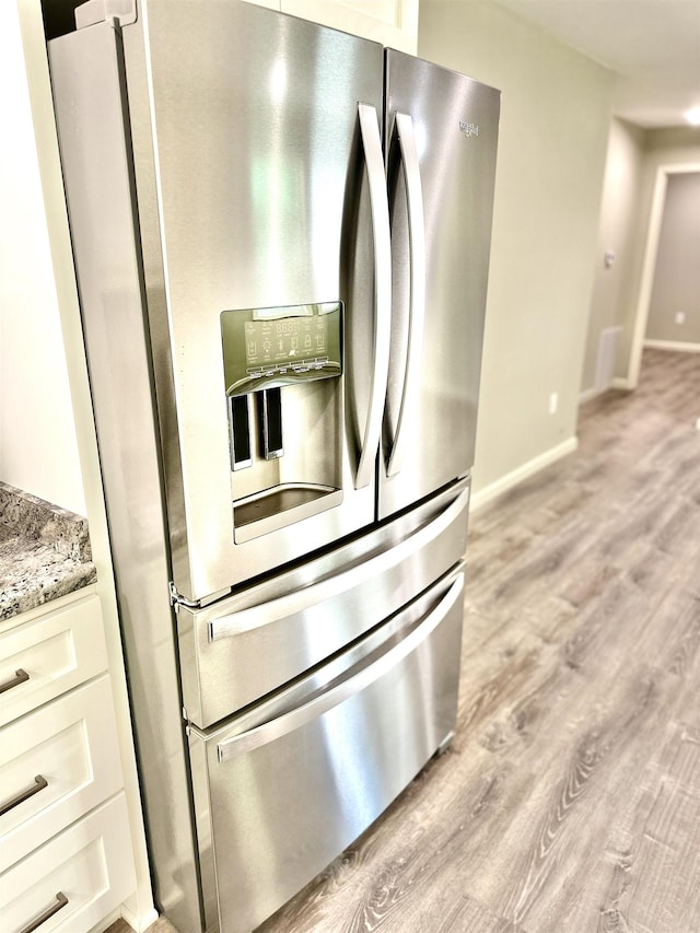 377 N 3rd St Unit B, Black Rock, AR 72415 - kitchen view of stainless steel fridge with ice dispenser, light wood-type flooring, light stone countertops, and white cabinets