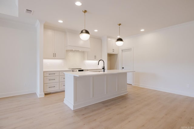 127 Edgewood Cir, Little Rock, AR 72223 - kitchen with backsplash, light countertops, a center island with sink, light wood-style flooring, and hanging light fixtures