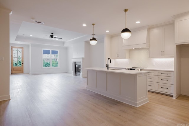 127 Edgewood Cir, Little Rock, AR 72223 - kitchen featuring custom exhaust hood, a kitchen island with sink, light countertops, light wood-type flooring, and recessed lighting