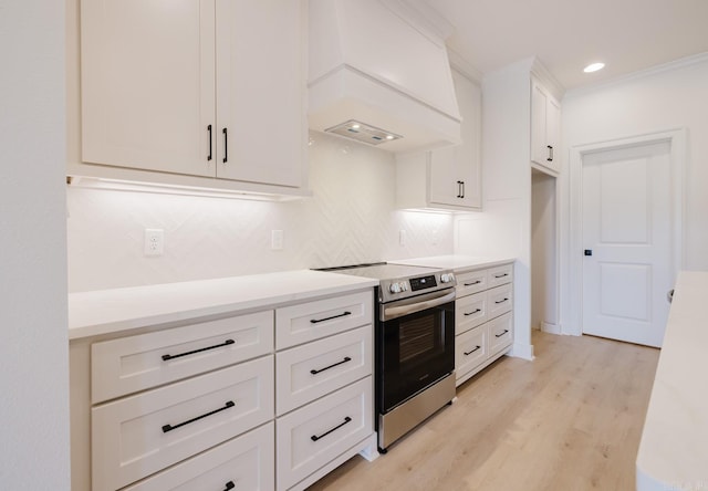127 Edgewood Cir, Little Rock, AR 72223 - kitchen featuring stainless steel electric range, custom range hood, decorative backsplash, light wood-style flooring, and white cabinetry