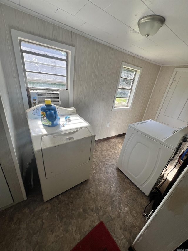 washroom featuring washing machine and clothes dryer, cooling unit, wooden walls, and dark flooring