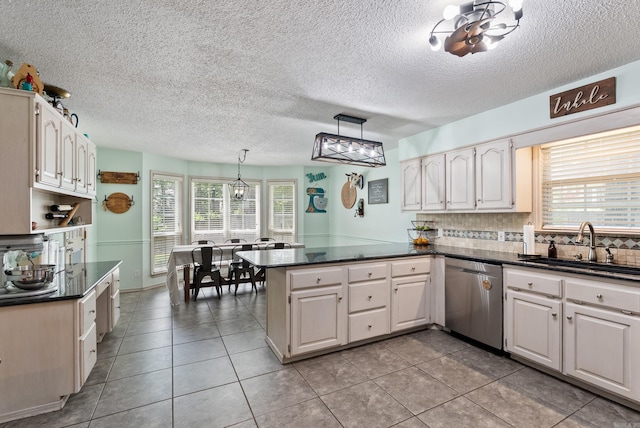 105 Little Creek Rd, Sherwood, AR 72120 - kitchen with stainless steel dishwasher, a peninsula, dark countertops, healthy amount of natural light, and a textured ceiling