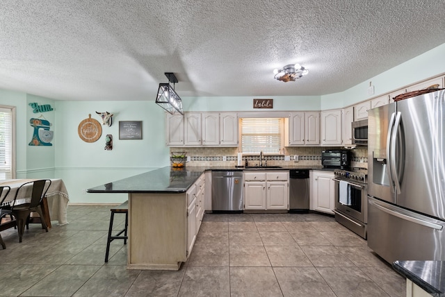 105 Little Creek Rd, Sherwood, AR 72120 - kitchen with stainless steel appliances, a peninsula, dark countertops, tasteful backsplash, and a breakfast bar