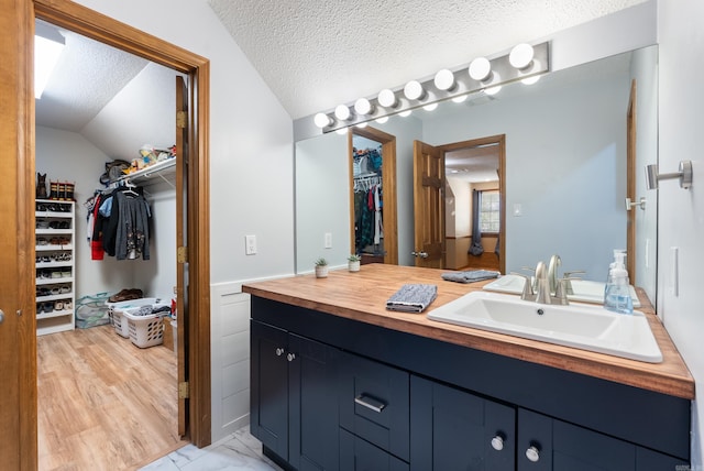 105 Little Creek Rd, Sherwood, AR 72120 - bathroom with vanity, a spacious closet, lofted ceiling, and a textured ceiling