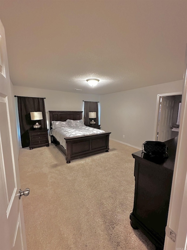 bedroom featuring light colored carpet and a textured ceiling