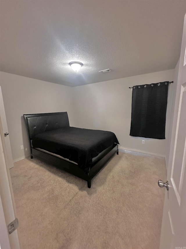 bedroom featuring light carpet and a textured ceiling