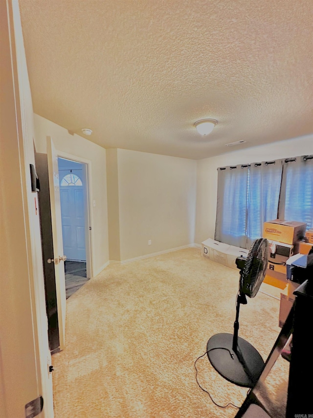 carpeted empty room with a textured ceiling and baseboards