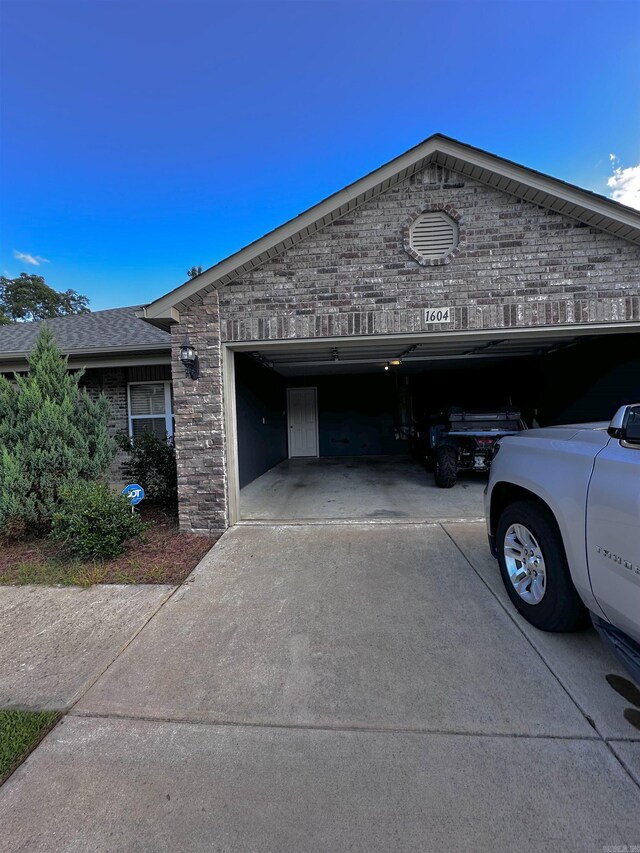 view of side of home featuring concrete driveway, an attached garage, and brick siding