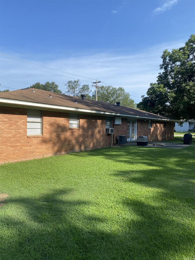 back of house featuring a lawn and brick siding