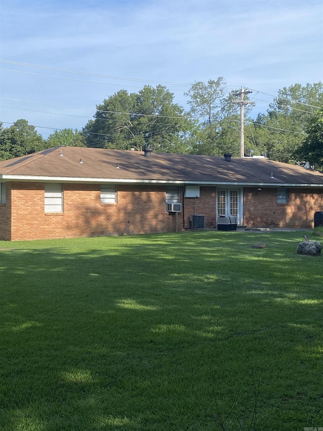 rear view of house featuring a yard, brick siding, and cooling unit