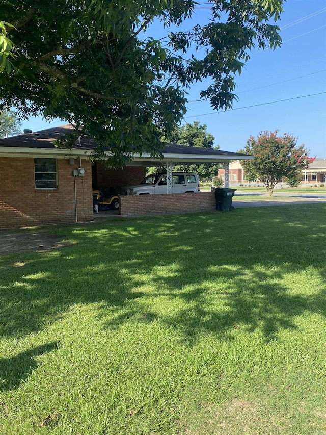 view of green lawn with a carport