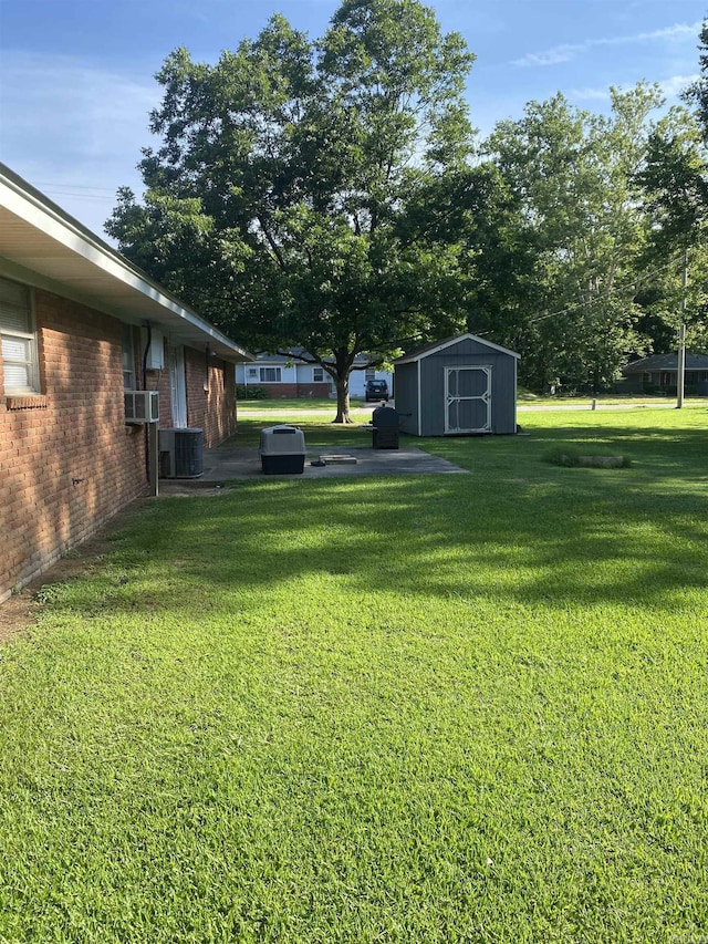 view of grassy yard with a storage shed and cooling unit