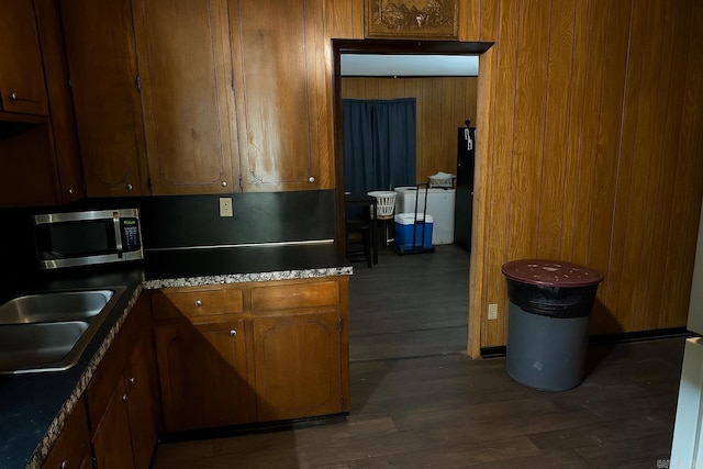 2111 Whyte Dr, North Little Rock, AR 72117 - kitchen featuring stainless steel microwave, dark wood-type flooring, brown cabinets, wood walls, and freestanding refrigerator