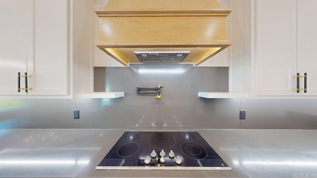 270 Arrowhead Rd, Greenbrier, AR 72058 - kitchen view of black electric cooktop, white cabinets, ventilation hood, and light countertops