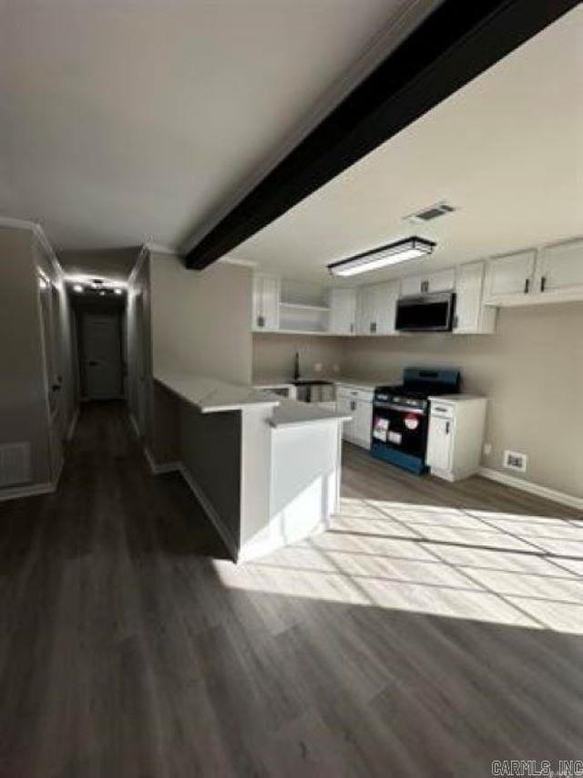 9701 Woodland Dr, Mabelvale, AR 72103 - kitchen with electric range, stainless steel microwave, white cabinets, a peninsula, and beamed ceiling