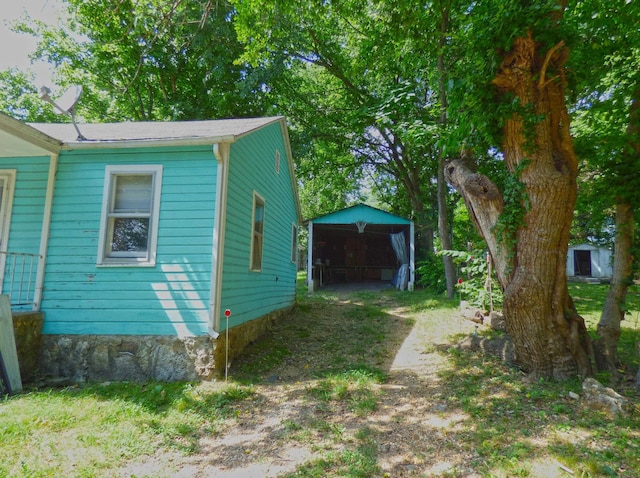 102 E Second St, Hardy, AR 72542 - view of home's exterior featuring a detached carport, dirt driveway, and an outdoor structure