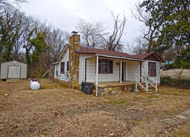 104 W First St, Hardy, AR 72542 - view of front of home with a porch, a shed, a chimney, and a shingled roof