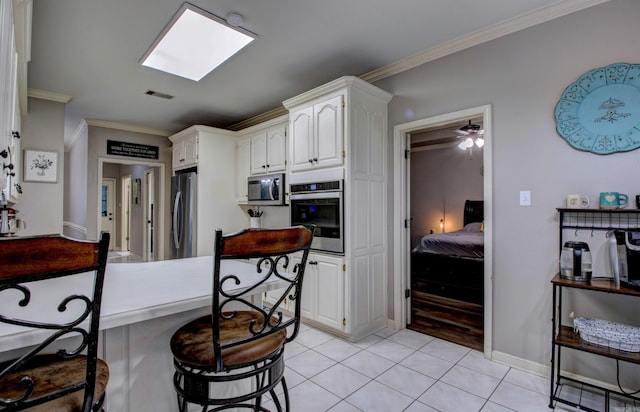 4600 Lexington Park Cir, Bryant, AR 72022 - kitchen with appliances with stainless steel finishes, crown molding, light tile patterned floors, white cabinets, and a breakfast bar area