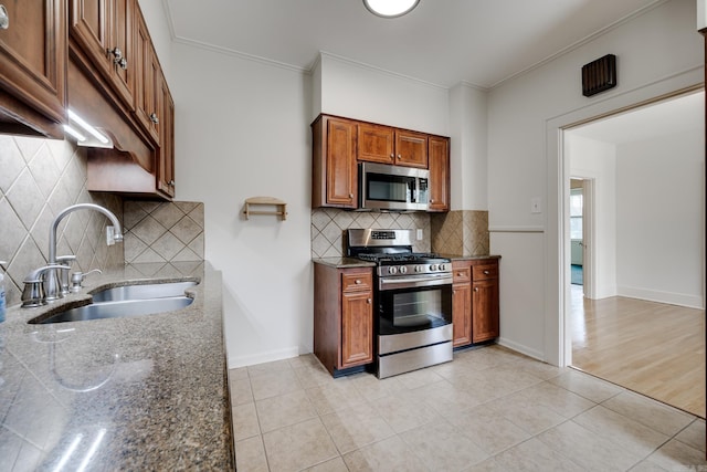 205 S Martin St, Little Rock, AR 72205 - kitchen featuring stainless steel appliances, tasteful backsplash, brown cabinetry, dark stone counters, and crown molding