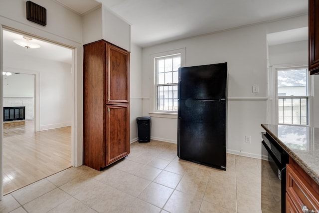 205 S Martin St, Little Rock, AR 72205 - kitchen with black appliances, light stone counters, brown cabinetry, light tile patterned floors, and a glass covered fireplace