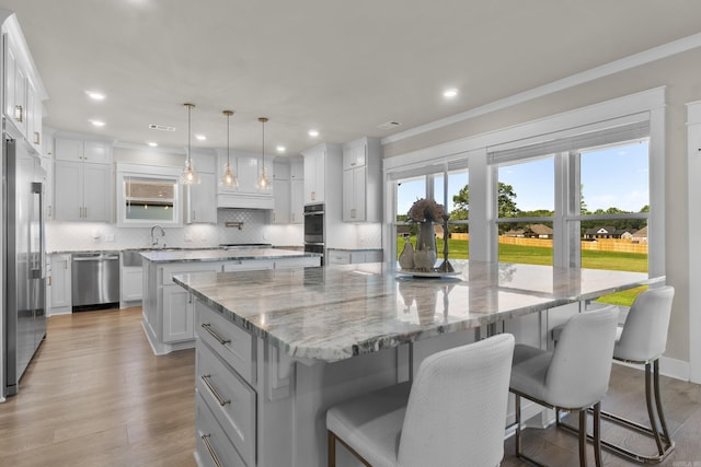 148 Irene Cir, Greenbrier, AR 72058 - kitchen featuring a large island, appliances with stainless steel finishes, tasteful backsplash, a breakfast bar area, and wood finished floors