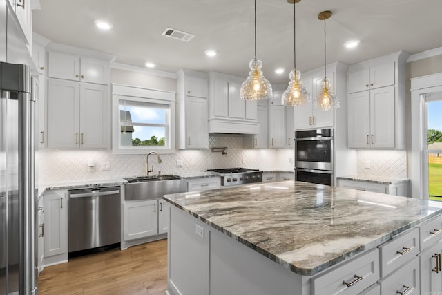 148 Irene Cir, Greenbrier, AR 72058 - kitchen featuring appliances with stainless steel finishes, decorative backsplash, a kitchen island, light wood-type flooring, and white cabinets