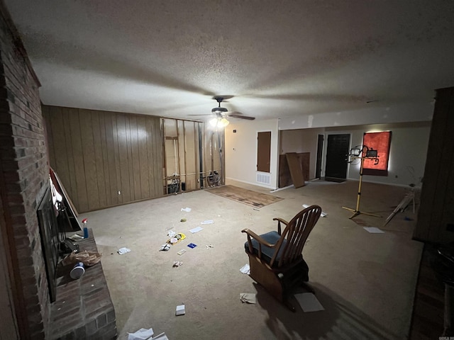 9313 Timber Valley Rd, Little Rock, AR 72204 - unfurnished living room with wood walls, ceiling fan, a textured ceiling, and a brick fireplace