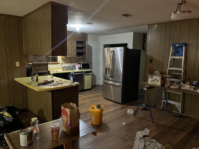 9313 Timber Valley Rd, Little Rock, AR 72204 - kitchen with stainless steel appliances, dark wood finished floors, a peninsula, light countertops, and wood walls