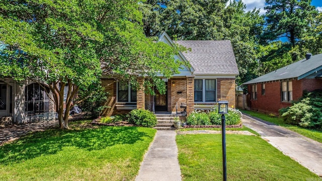 127 W F Ave, North Little Rock, AR 72116 - view of front facade with brick siding, a front yard, a porch, and roof with shingles