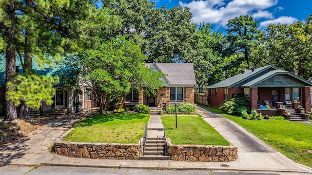 127 W F Ave, North Little Rock, AR 72116 - view of property hidden behind natural elements with a porch, a front yard, brick siding, and driveway