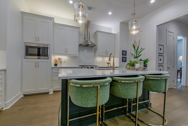 101 Mergeron Ct, Little Rock, AR 72212 - kitchen featuring stainless steel microwave, light wood-style floors, a breakfast bar, light countertops, and backsplash