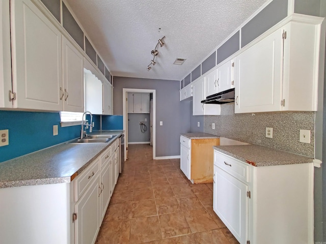 18 Langford St, Ward, AR 72176 - kitchen with backsplash, white cabinets, under cabinet range hood, track lighting, and a textured ceiling