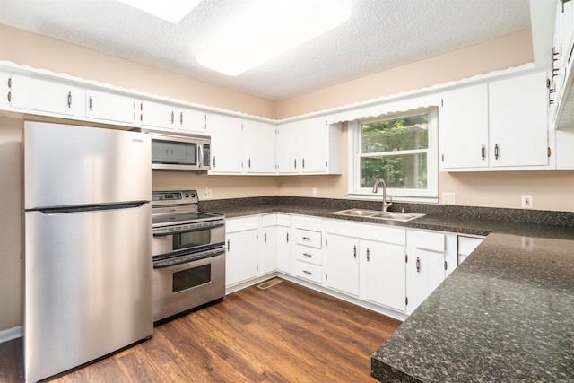 1 Bahia Ln, Hot Springs Village, AR 71909 - kitchen with stainless steel appliances, dark wood-style flooring, a textured ceiling, white cabinets, and dark stone countertops