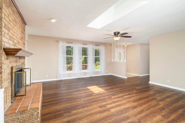 1 Bahia Ln, Hot Springs Village, AR 71909 - unfurnished living room featuring a textured ceiling, wood finished floors, a fireplace, ceiling fan, and a skylight