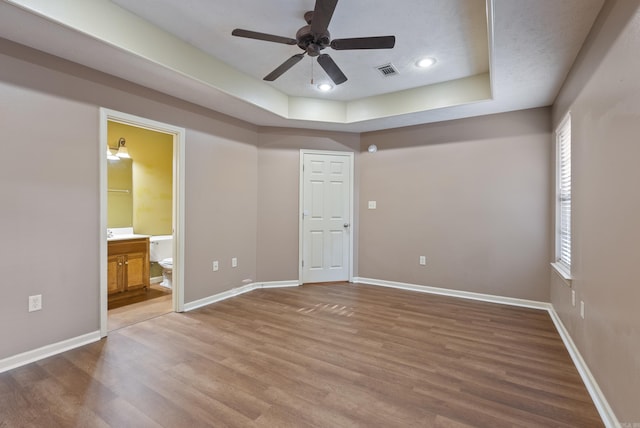 970 Wineberry, Conway, AR 72034 - unfurnished bedroom with a tray ceiling, wood finished floors, ensuite bathroom, and recessed lighting