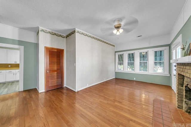 408 N 3rd St, Cabot, AR 72023 - unfurnished living room featuring a brick fireplace, a ceiling fan, light wood-type flooring, and a textured ceiling