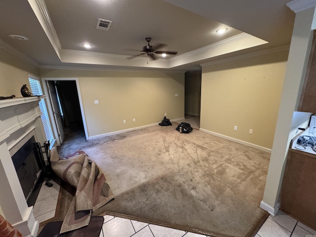 unfurnished living room with a raised ceiling, ornamental molding, carpet, a ceiling fan, and a fireplace