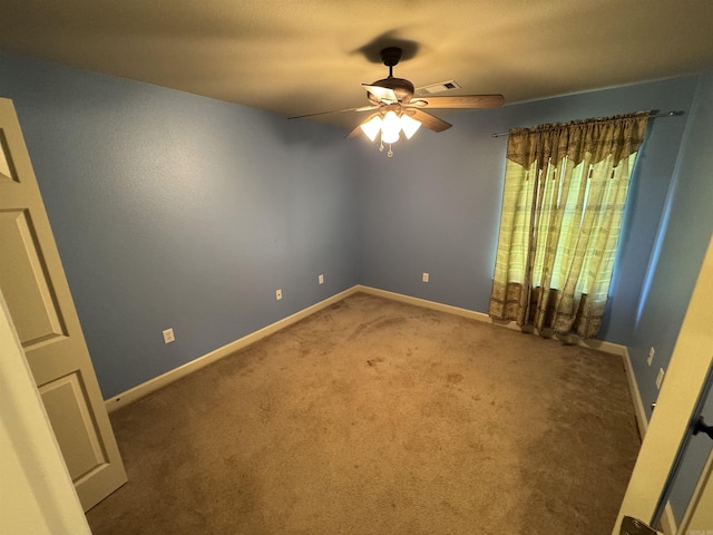carpeted empty room with ceiling fan and baseboards