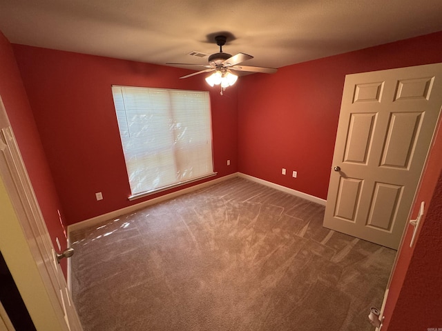 carpeted spare room featuring a ceiling fan and baseboards