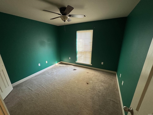 carpeted spare room with baseboards and ceiling fan
