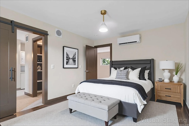 128 Dickson Dr, Little Rock, AR 72207 - bedroom with a wall mounted AC, a barn door, and wood finished floors
