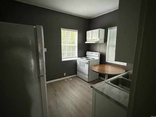 2417 Wolfe St, Little Rock, AR 72206 - kitchen with white electric range, freestanding refrigerator, light wood-style floors, white cabinets, and under cabinet range hood