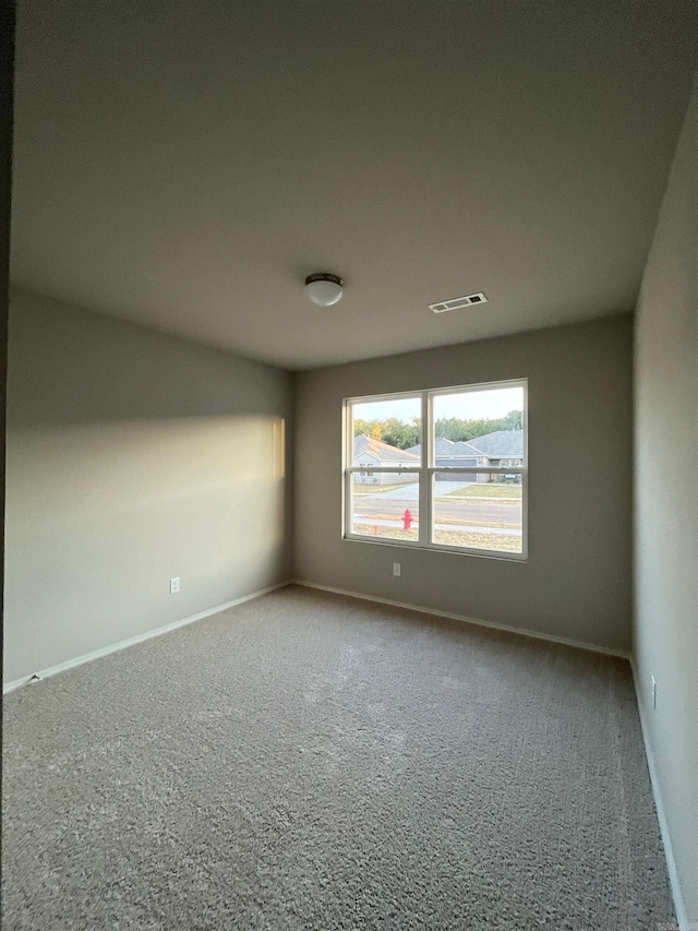 carpeted empty room featuring baseboards