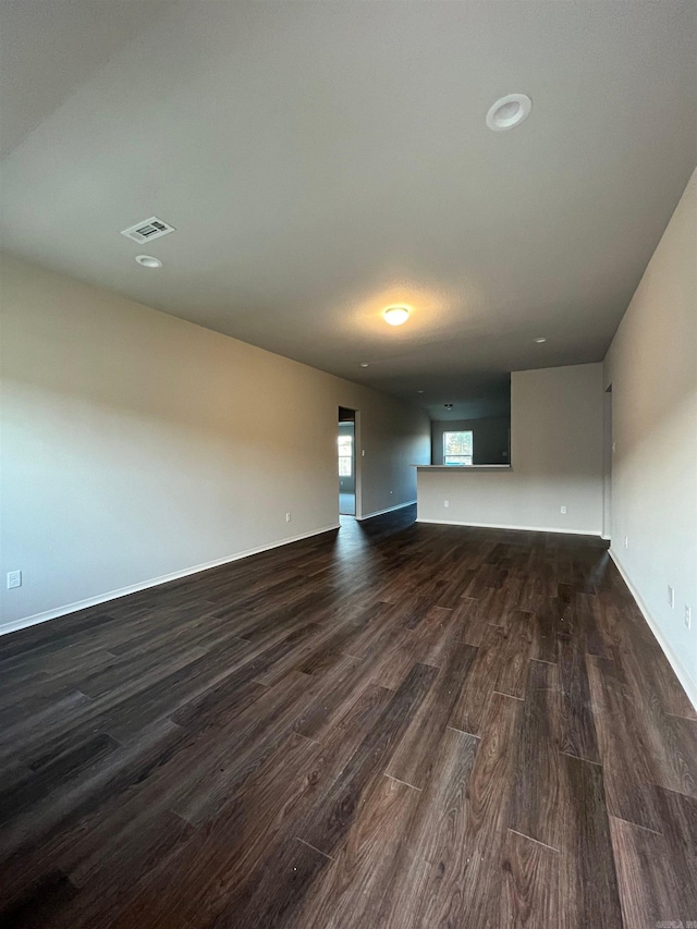 unfurnished living room with dark wood-type flooring and baseboards