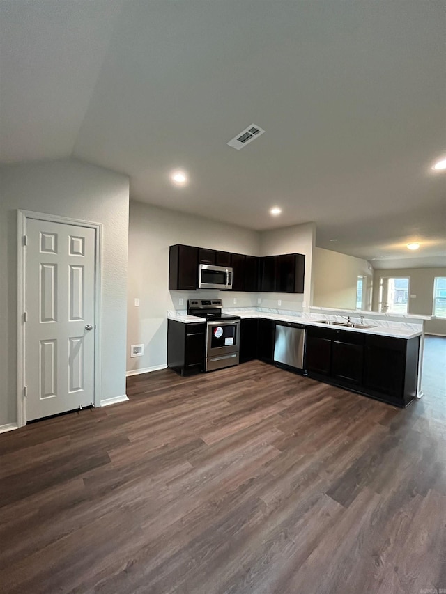 kitchen with stainless steel appliances, dark wood-type flooring, light countertops, dark cabinetry, and open floor plan