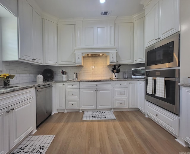 6413 Ram Rd, Mabelvale, AR 72103 - kitchen with stainless steel appliances, white cabinetry, light wood-type flooring, tasteful backsplash, and light stone countertops