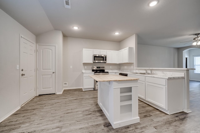 1375 Lacroix Ln, Conway, AR 72034 - kitchen featuring stainless steel appliances, a peninsula, arched walkways, light wood-style floors, and lofted ceiling